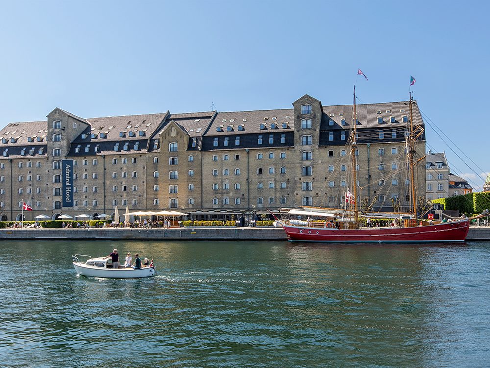 Hotel Admiral fra vandet med rød sejlbåd i forgrunden / Artelia / Rådgivende Ingeniører